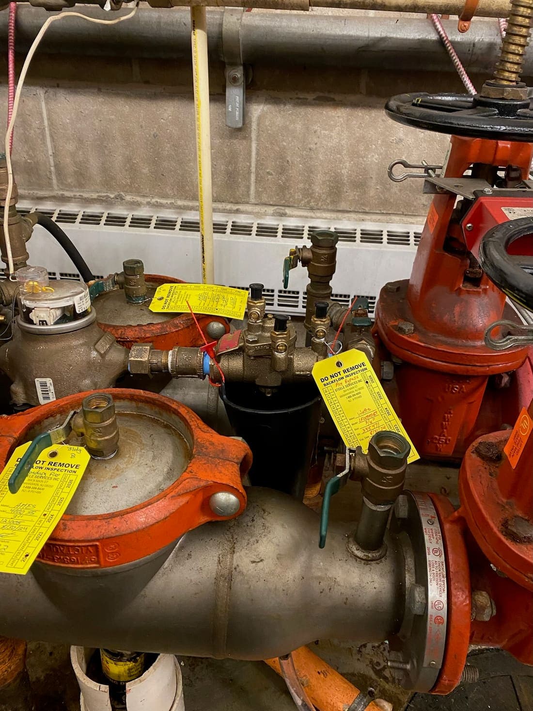 Backflow prevention assembly carrying three Steele Services inspection tags