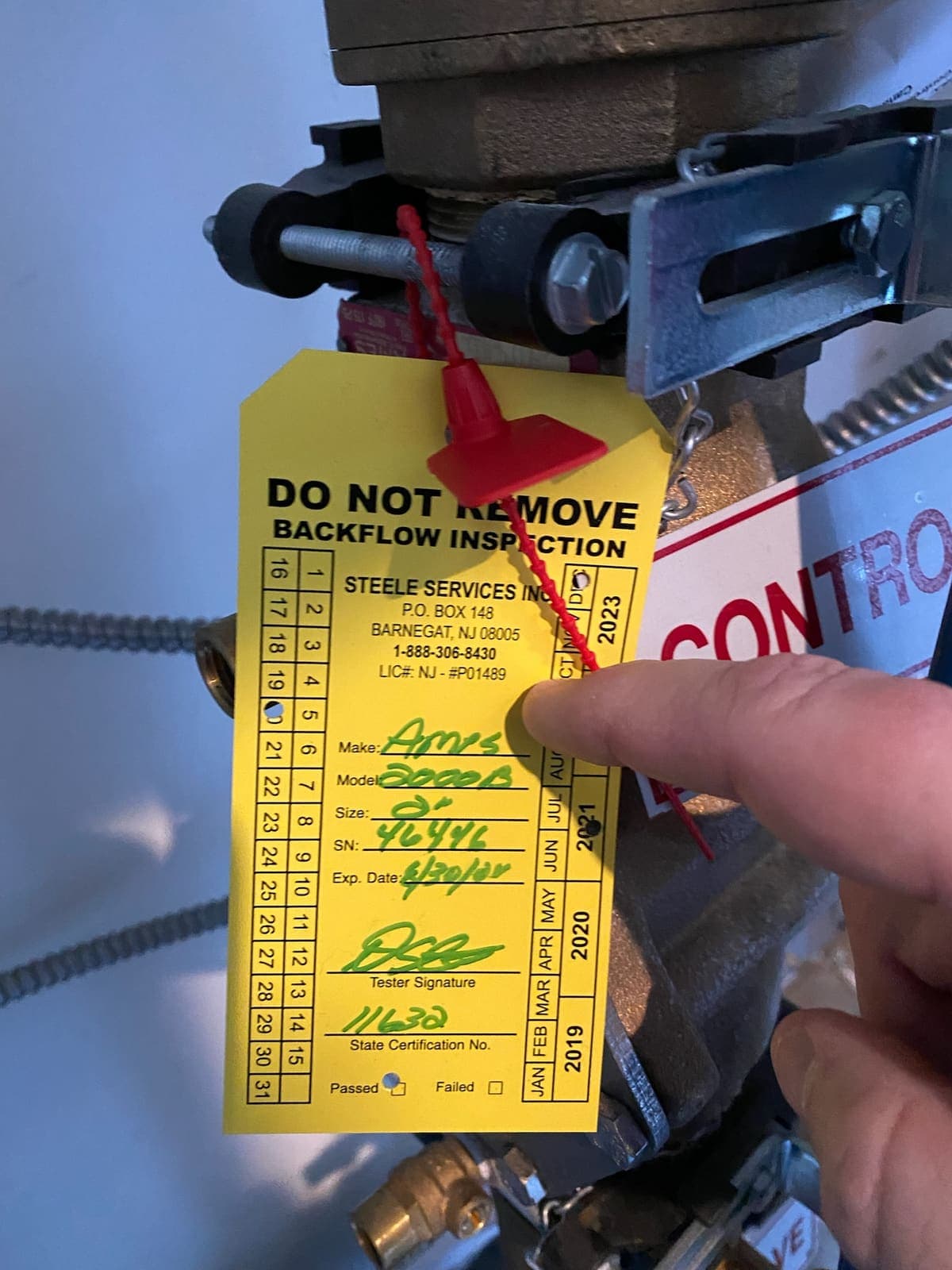 Steele Services backflow inspection tag, marked passed, sealed to a tested assembly