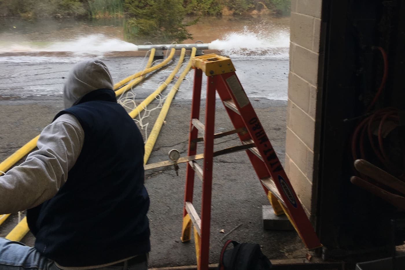 Steele technician running a full-flow test, discharge hose flowing to open water