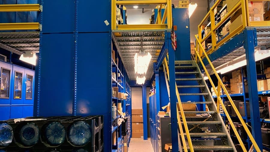 Multi-level parts storage mezzanine with steel shelving and stair access