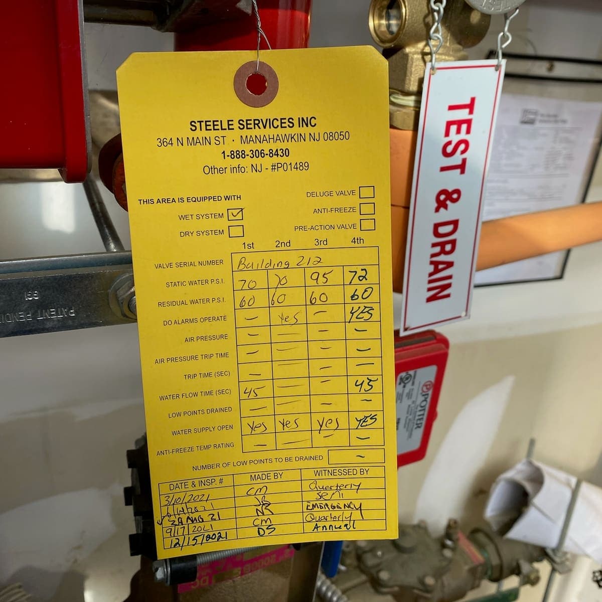 Steele Services wet-system inspection tag recording four dated quarterly and annual tests
