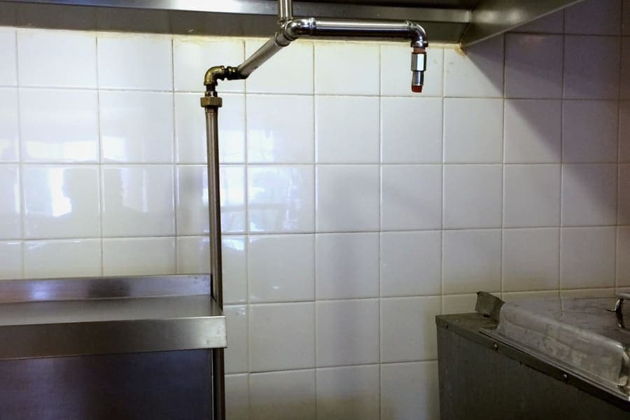 Brass kitchen hood suppression nozzle above a cooking line