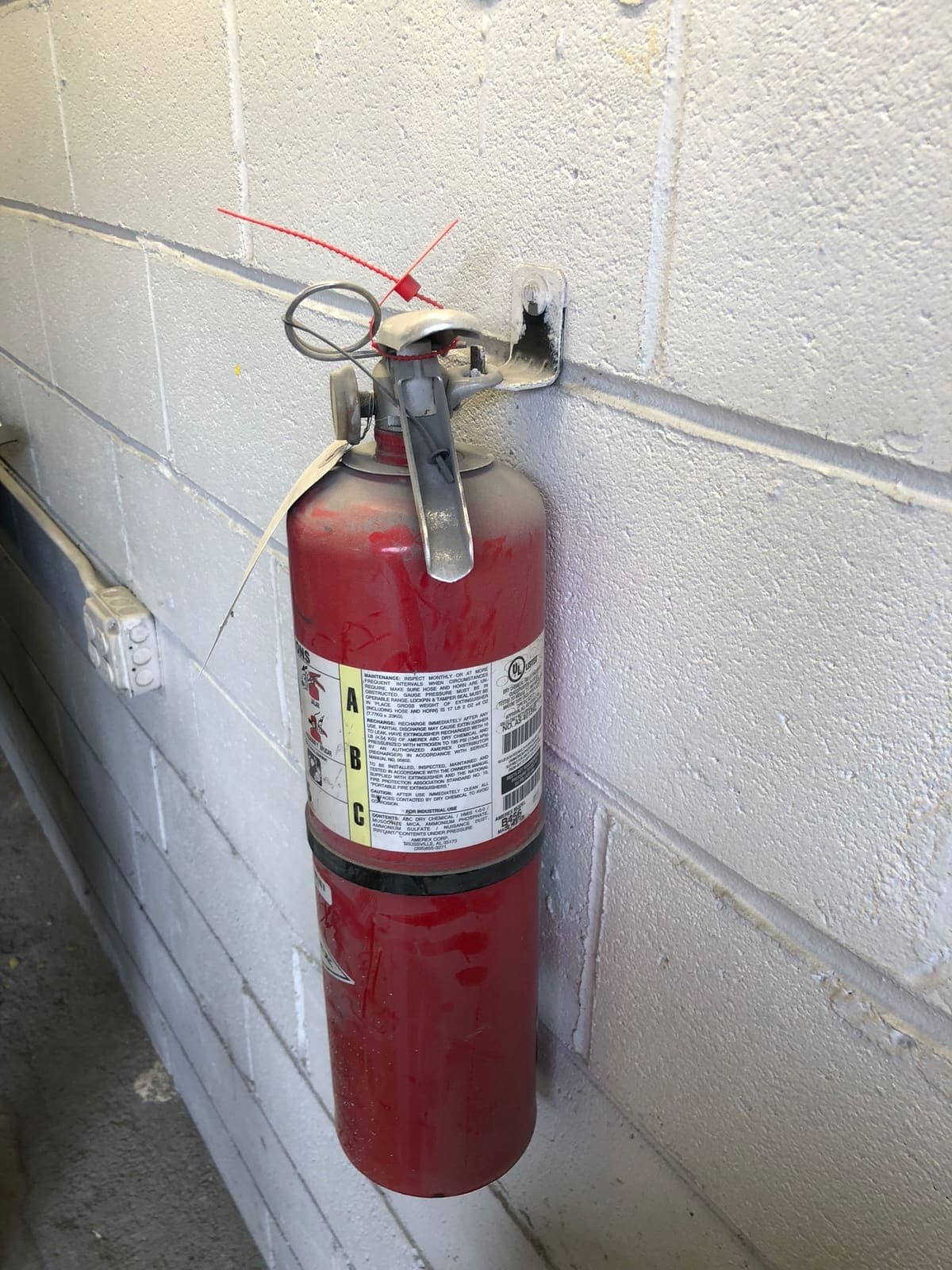 Wall-mounted ABC portable fire extinguisher with a current inspection tag