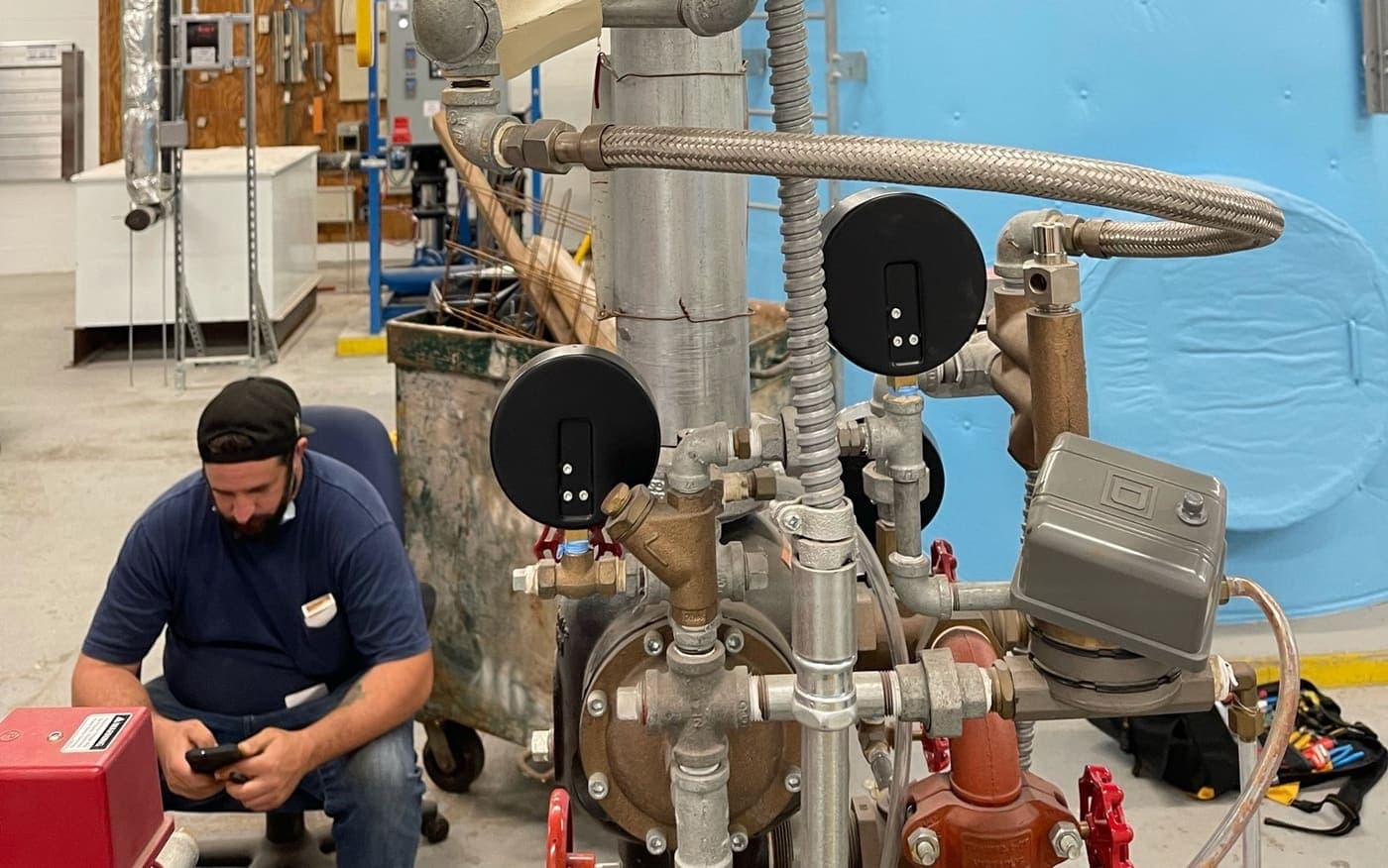 Steele technician working at a gauged backflow and riser assembly in a plant room